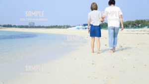 【沖縄】砂浜を歩くカップル 写真素材
